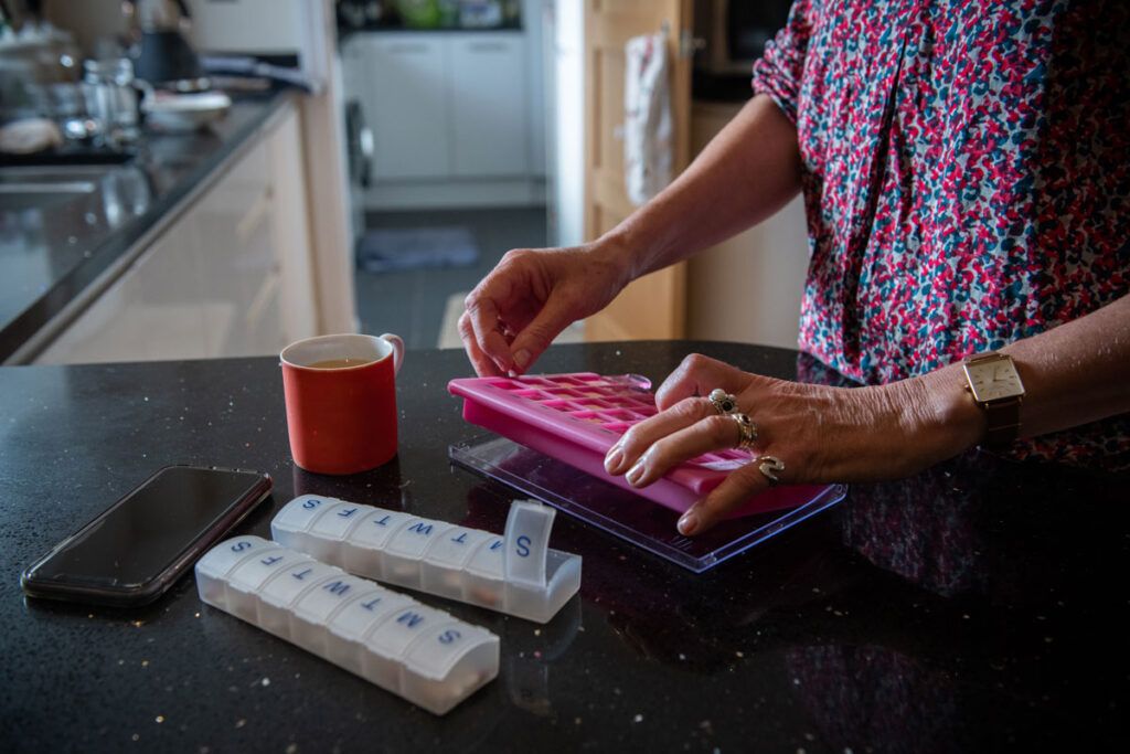 An adult sorting pills into a pill organizer, considering the benefits of beta blockers.