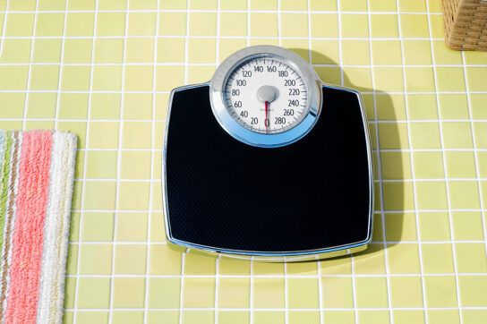 Bathroom scales next to a bath mat representing Vyvanse weight loss