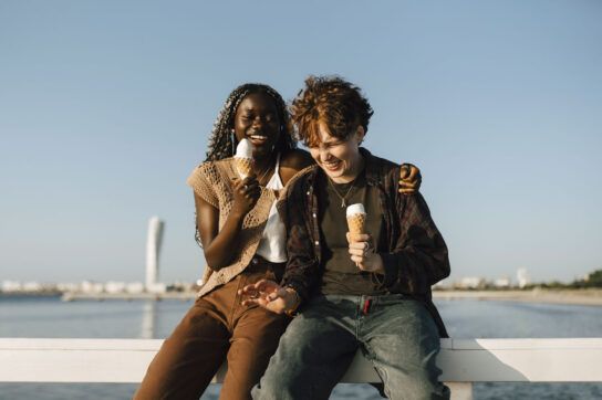 Two adolescents living with generalized anxiety disorder, laughing and eating ice cream.