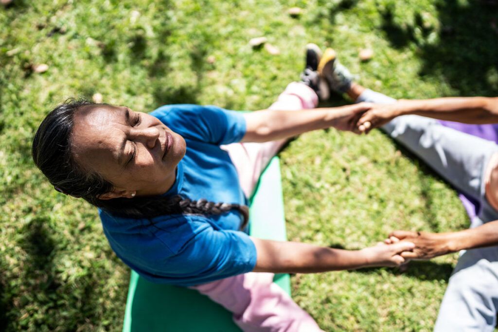 Person sat in a park doing yoga to depict treatment options for heat regulation, such as supplements.