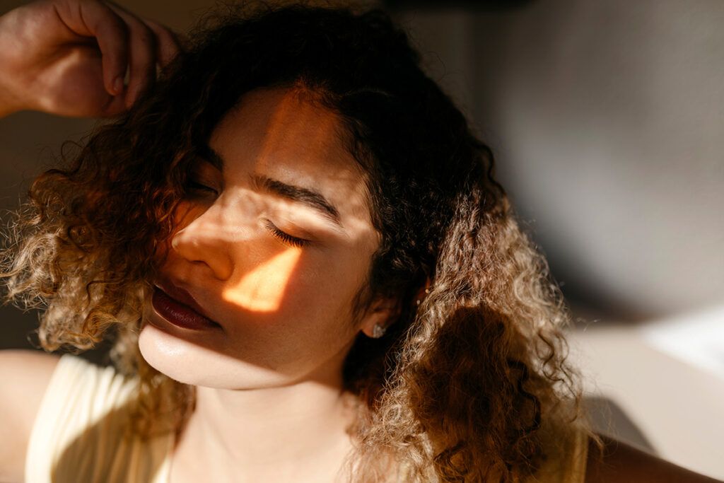 Female laying down with a patch of sunlight reflected on her face.