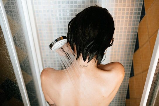 A person shown from the waist up using a handheld shower.