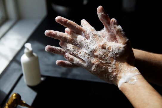 Someone washing their hands in a sink with a thick soap lather covering their hands. This is one of the things to be mindful of when it comes to preventing the 5 hepatitis types