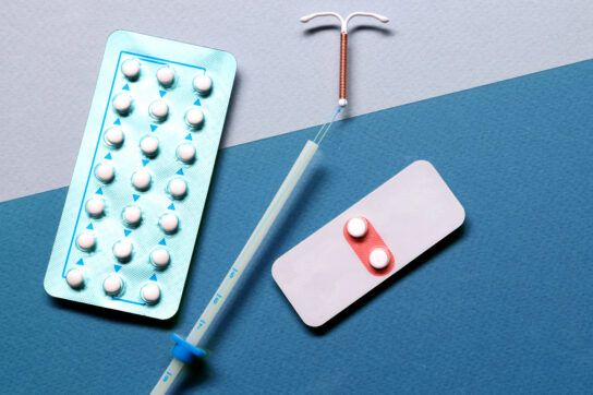Various birth control options displayed on a surface, such as pill packets and a copper UTI.Various birth control options displayed on a surface, such as pill packets and a copper UTI.