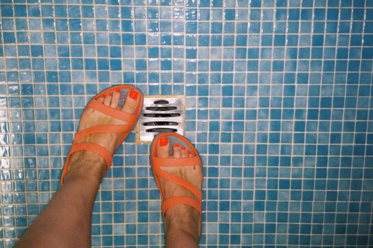 A person wearing sandals in a public shower, a way to get rid of athlete's foot.