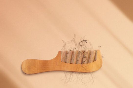 A hair comb with loose hair stuck in between the bristles.
