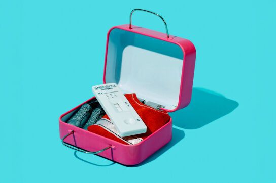A miniature pink suitcase with a COVID test inside.