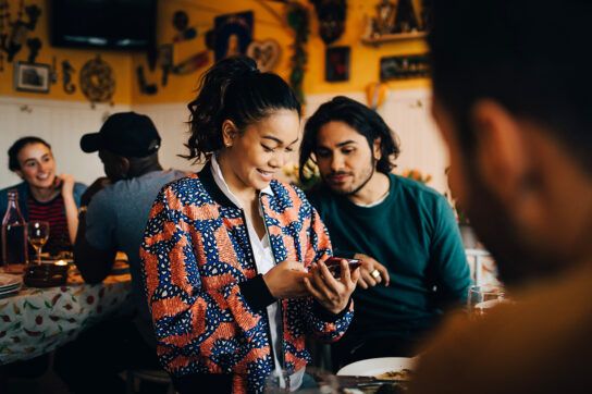 Two people sat in a restaurant looking at a phone.