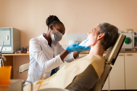 Female dentist performing exam on female patient in dentist's chair