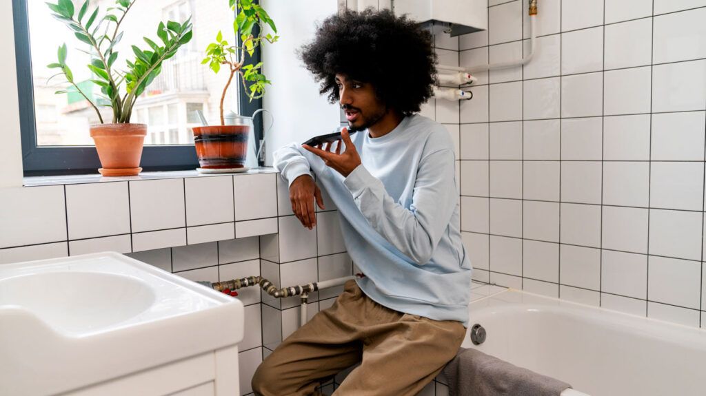 A teen sitting in the bathroom on the phone with their doctor to get advice about how to proceed after missing a dose of amoxicillin