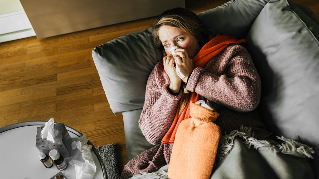 A person recovering from the flu, blowing their nose, after taking Tamiflu.