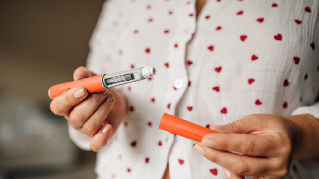 A person holding a GLP-1 pen vial.