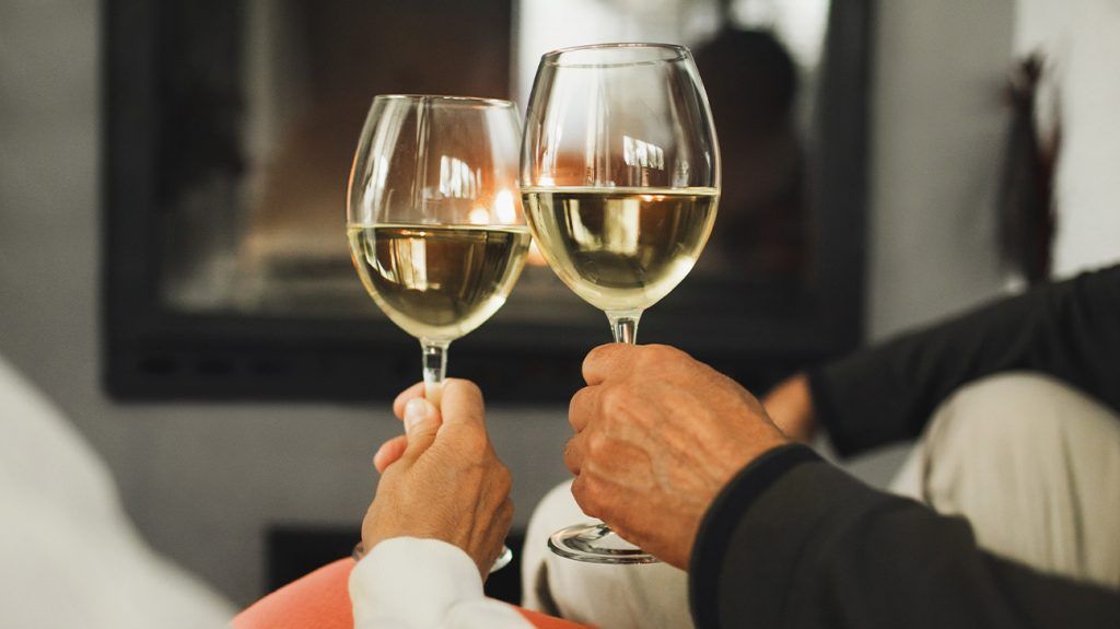 A couple holding glasses of white wine.