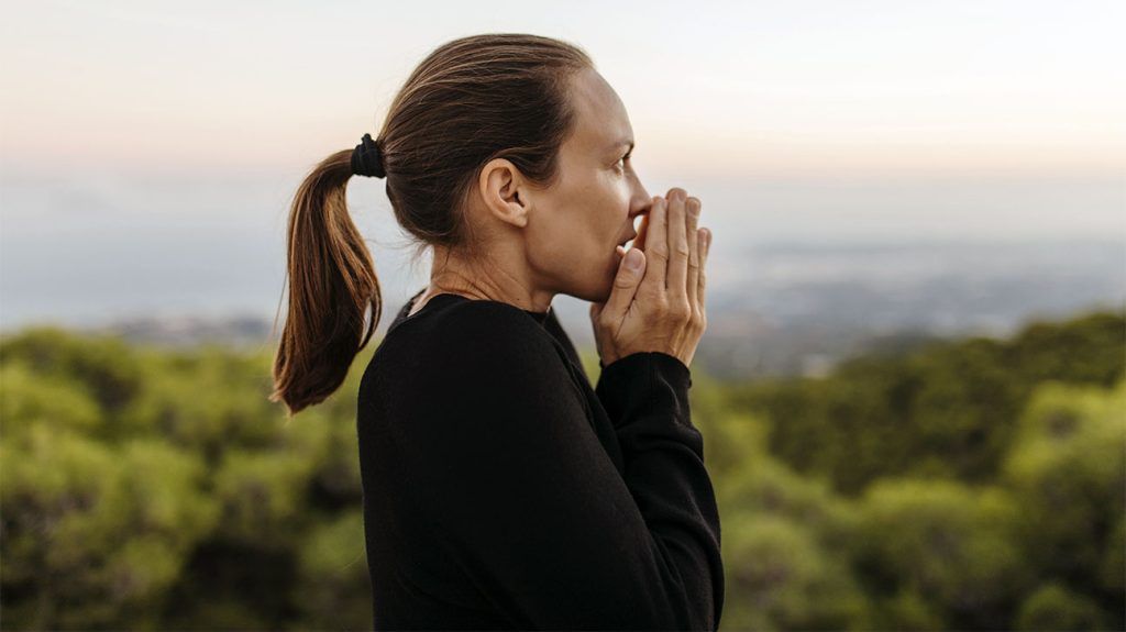A person outside coughing into their hands.