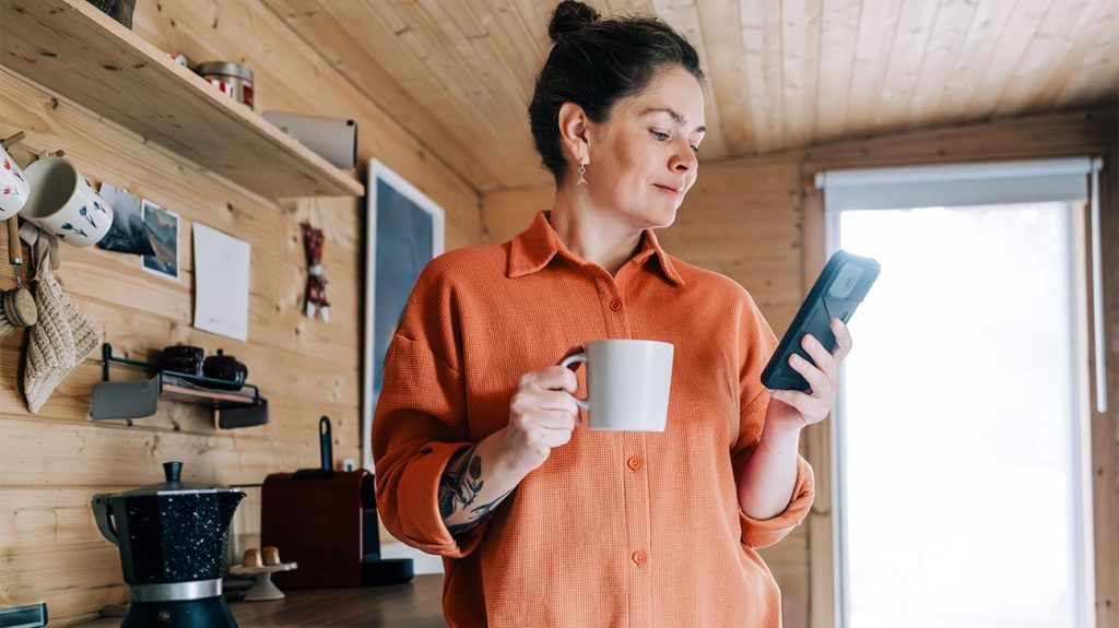 A person with a coffee researching prescription discount cards on their phone.