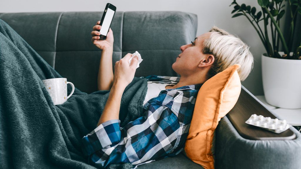 A person lying on a couch researching online care on social media.