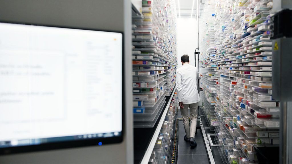 A pharmacist looking through shelves of medications.