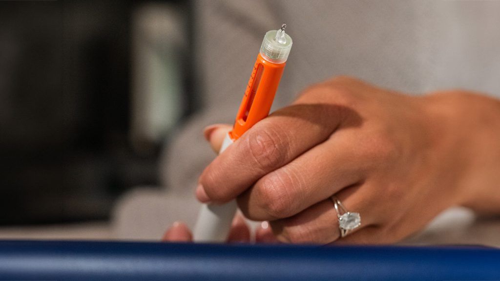 A person holding a GLP-1 injector.