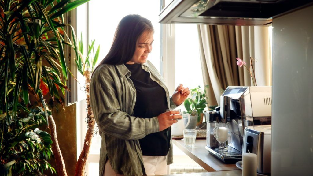 A plus-size woman making coffee in a cozy kitchen.