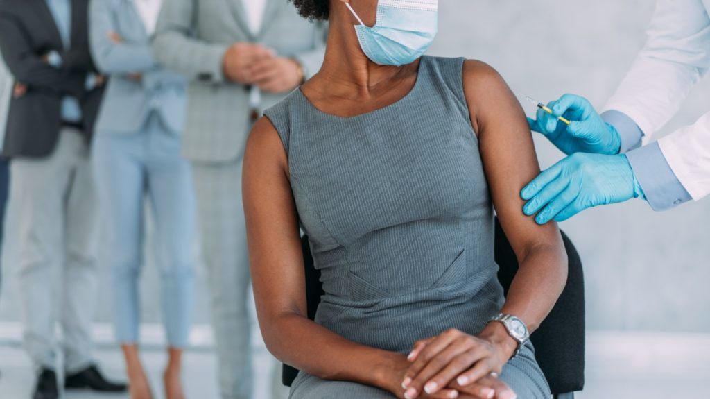 A businesswoman receiving a vaccine in an office.