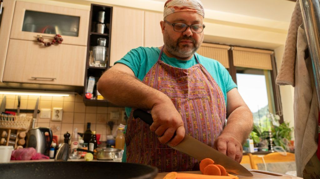 A plus-size man cutting carrots to make a healthy meal.