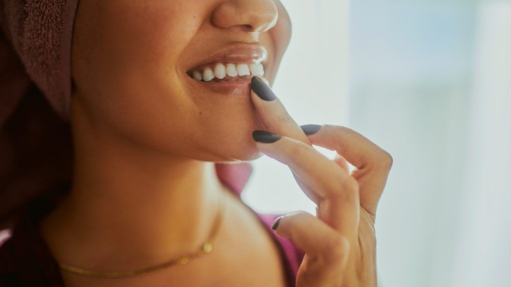A person applying lip balm to their lips.