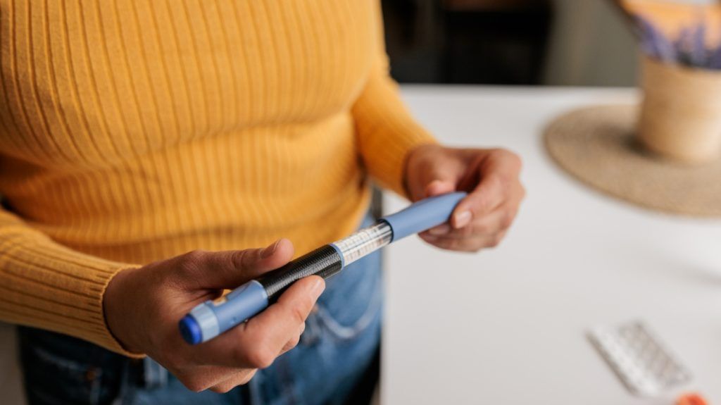 A person holding a GLP-1 injection pen.
