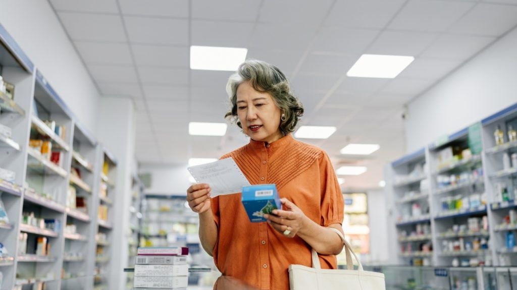 An older woman comparing OTC medications at a pharmacy.